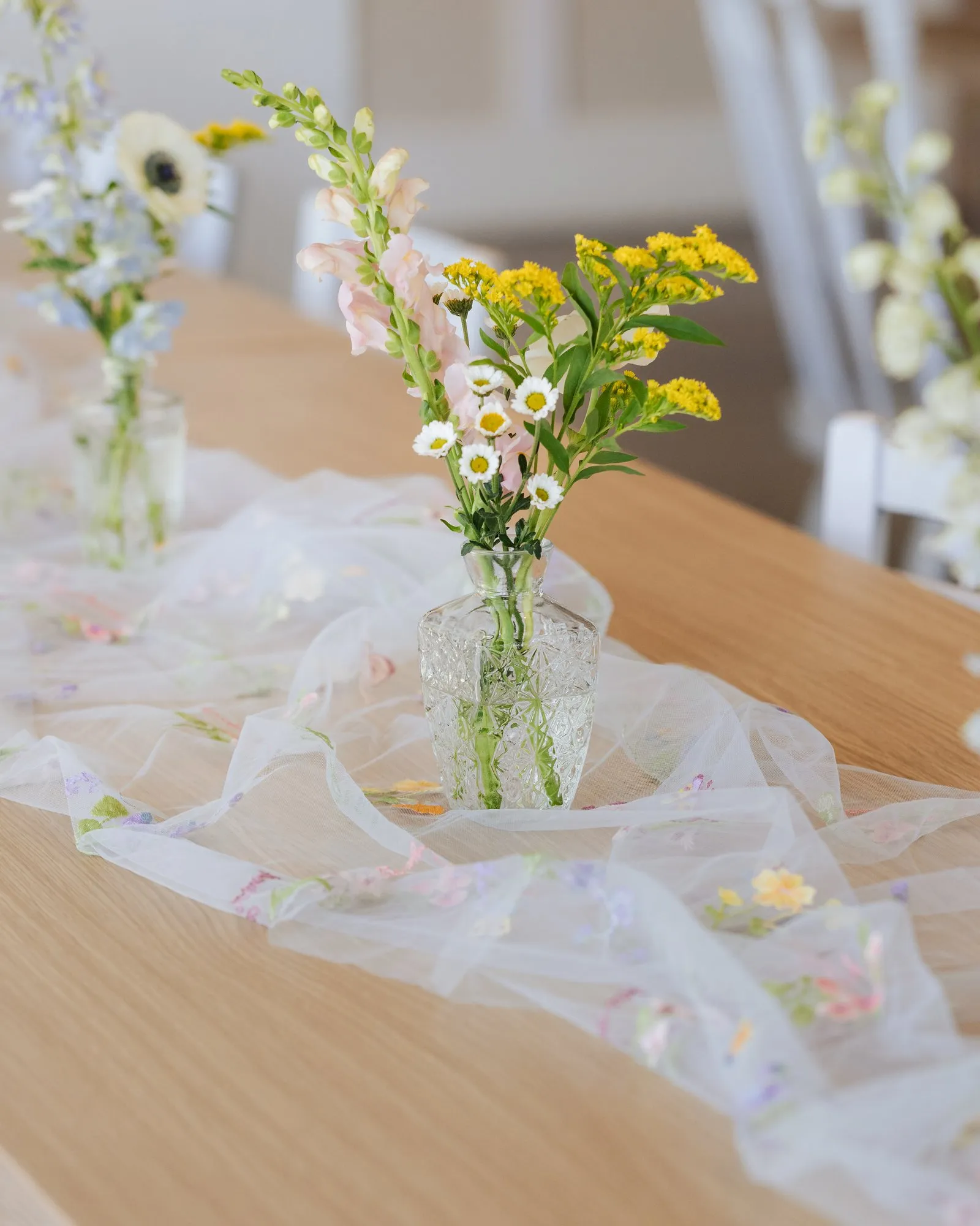 Wildflowers in cut-glass bud vases on an embroidered tulle runner